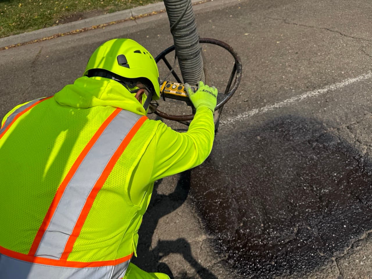 Operator directing the spray-injection hose onto a street repair